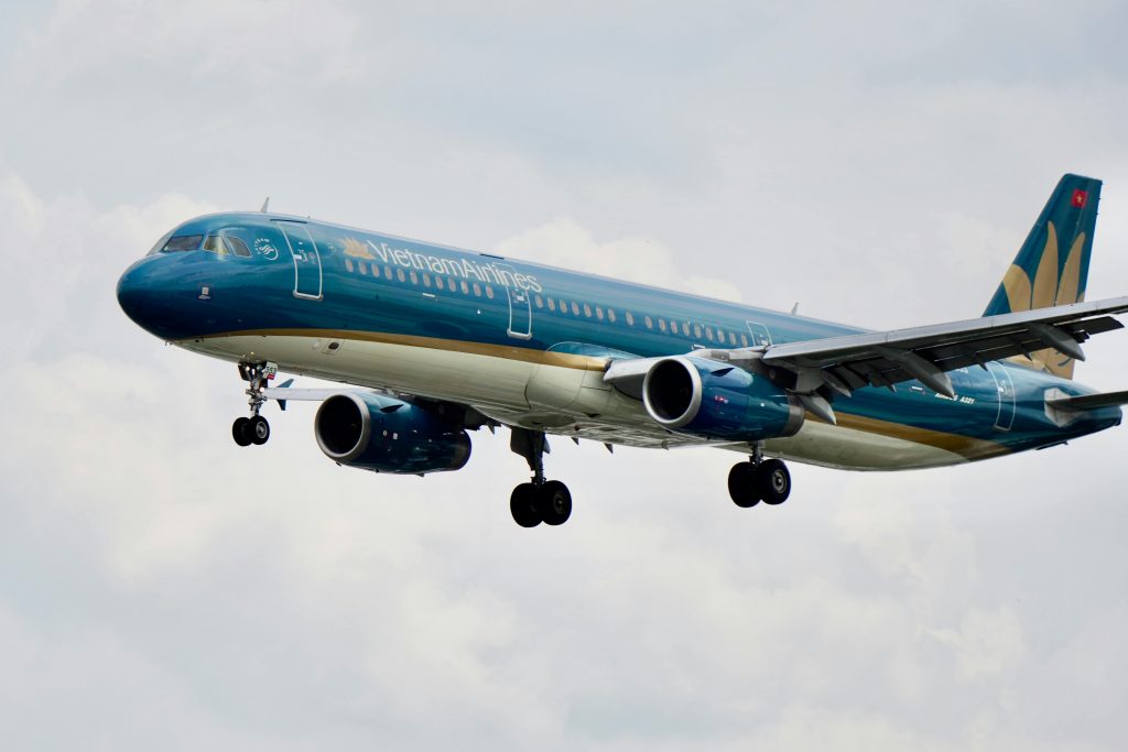 Detailed image of a Vietnam Airlines Airbus A321 aircraft during flight against a cloudy sky.